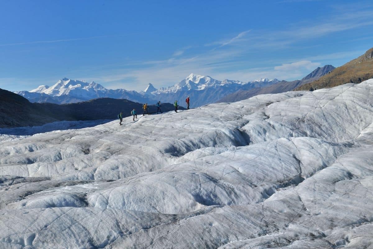 People walk across the Great Aletsch Glacier with the Matterhorn seen in the distance.