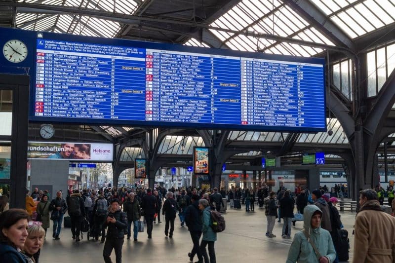 A large indicator board showing train arrivals and departures inside Zurich main station