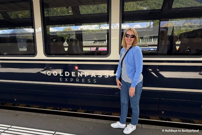 Woman standing beside the GoldenPass Express panoramic train